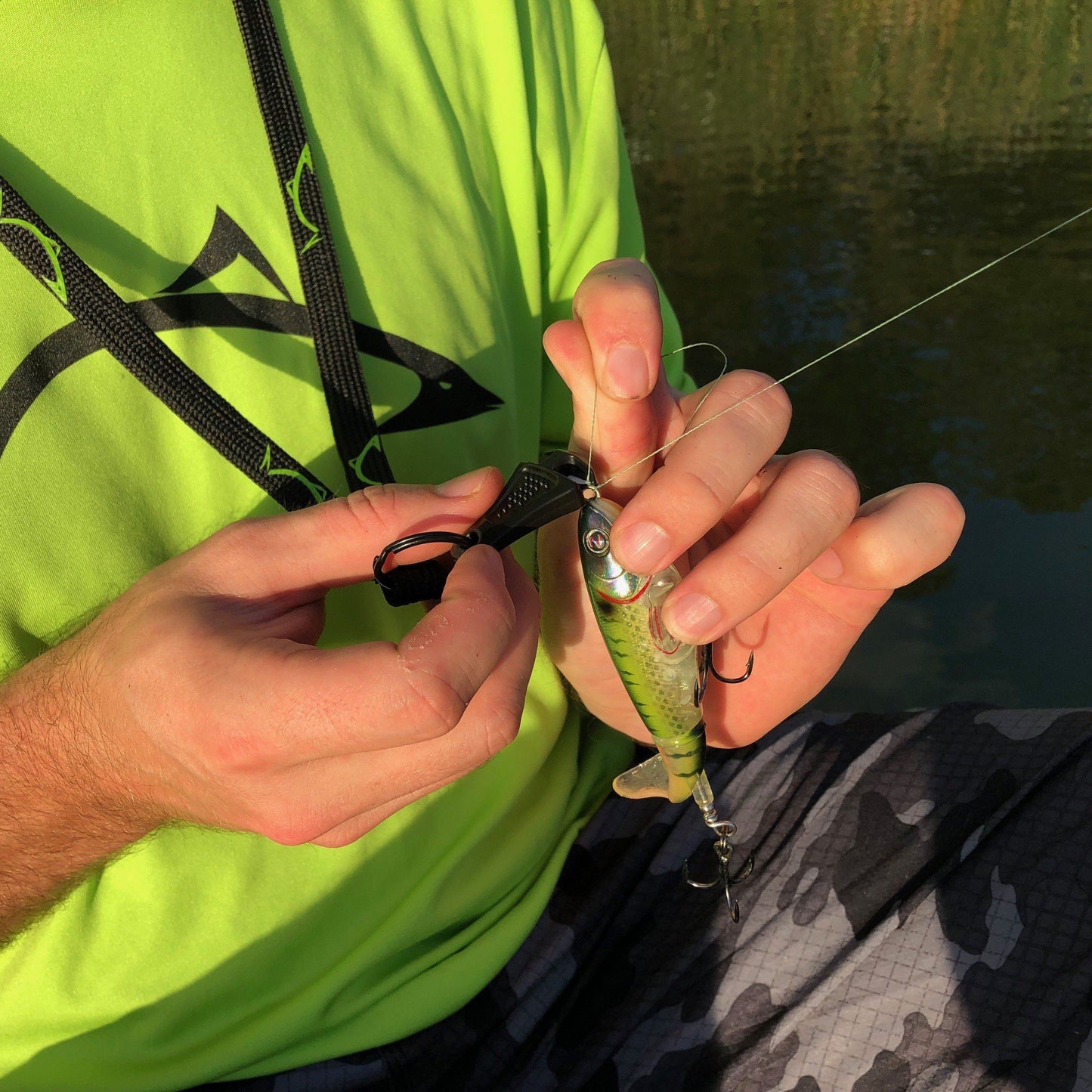 Man in green shirt cutting fishing line with the Line Cutterz Zipper Pull Fishing Line Cutter in his hand