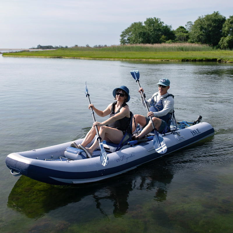 Two people paddling an inflatable ISLE Explorer 2-person kayak equipped with a Bixpy motor.