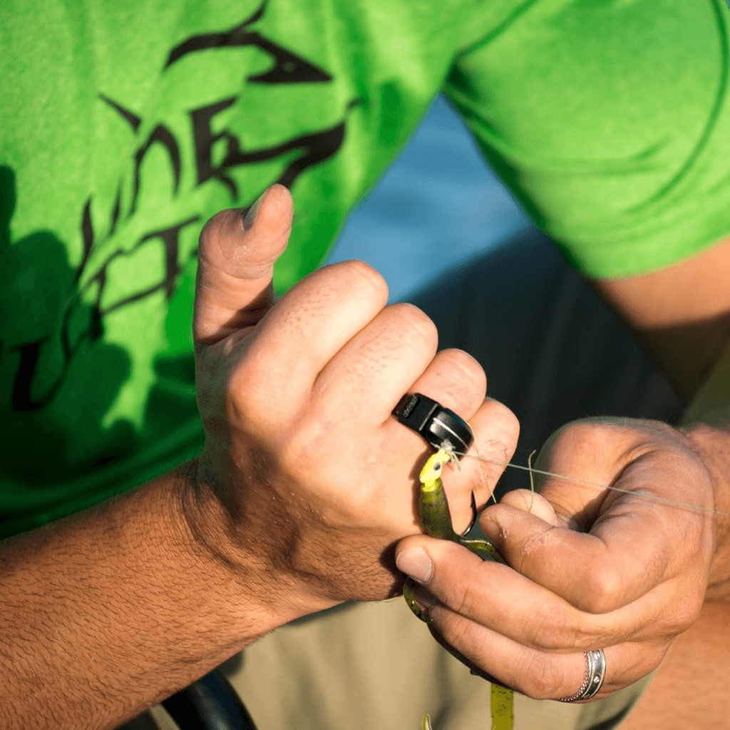 Man in green shirt with the Line Cutterz Ring Fishing Line Cutter on his ring finger cutting clear fishing line