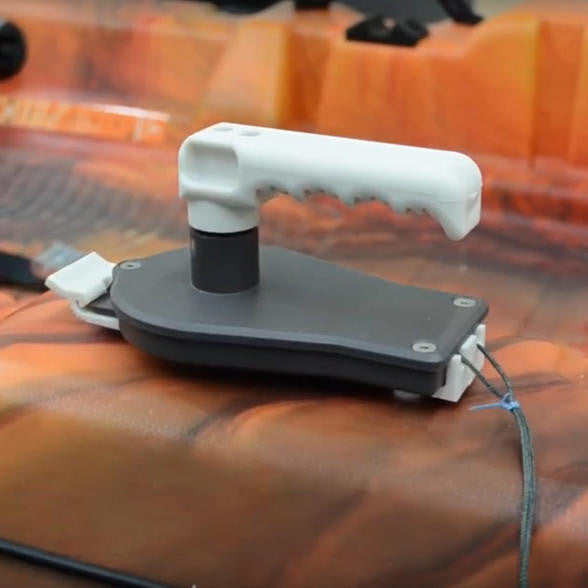 Close-up of a dark grey and white Bixpy Hand Steering Kit with a ridged handle and steering lines, mounted on an orange and red camouflage kayak deck.