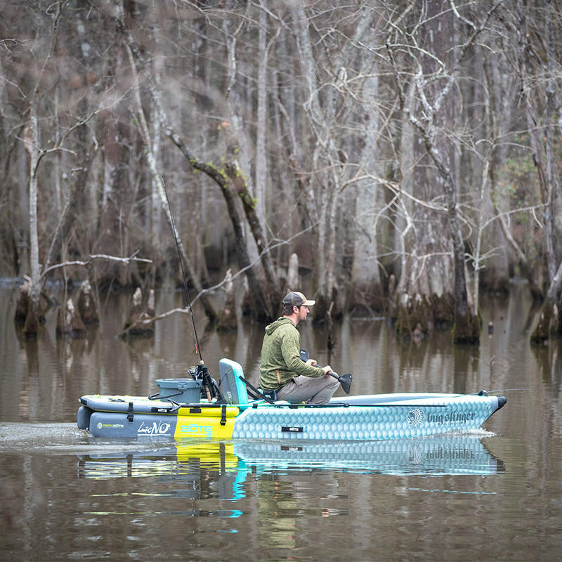Man cruising on BOTE fishing kayak powered by Bixpy J-2 Motor with Apex Pedal Drive Adapter, in wooded lake environment.