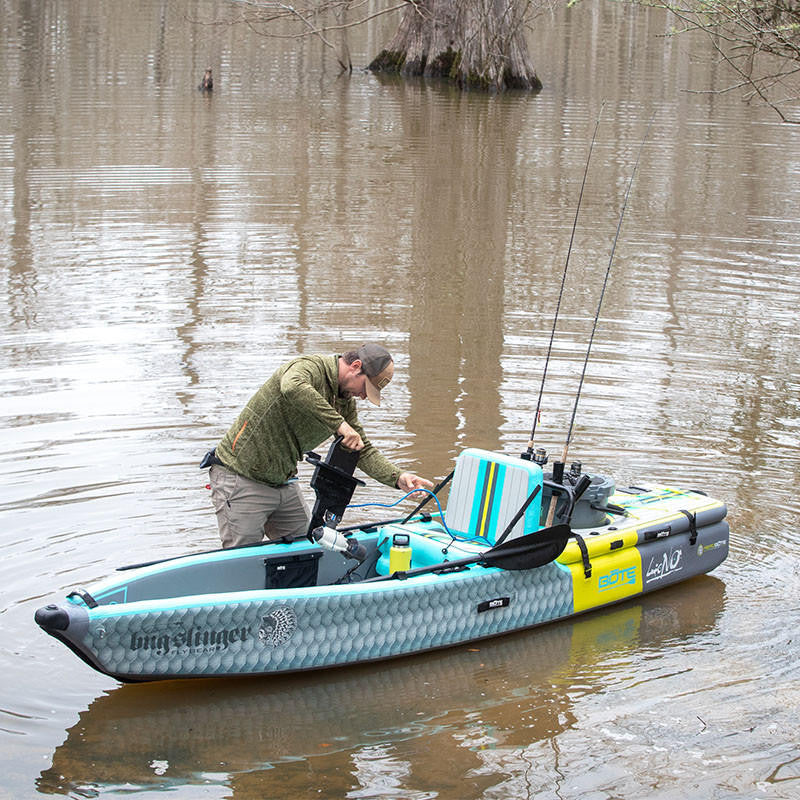 Man installing BOTE Apex Pedal Drive Adapter with Bixpy J-2 Motor on BOTE fishing kayak while standing in shallow water.