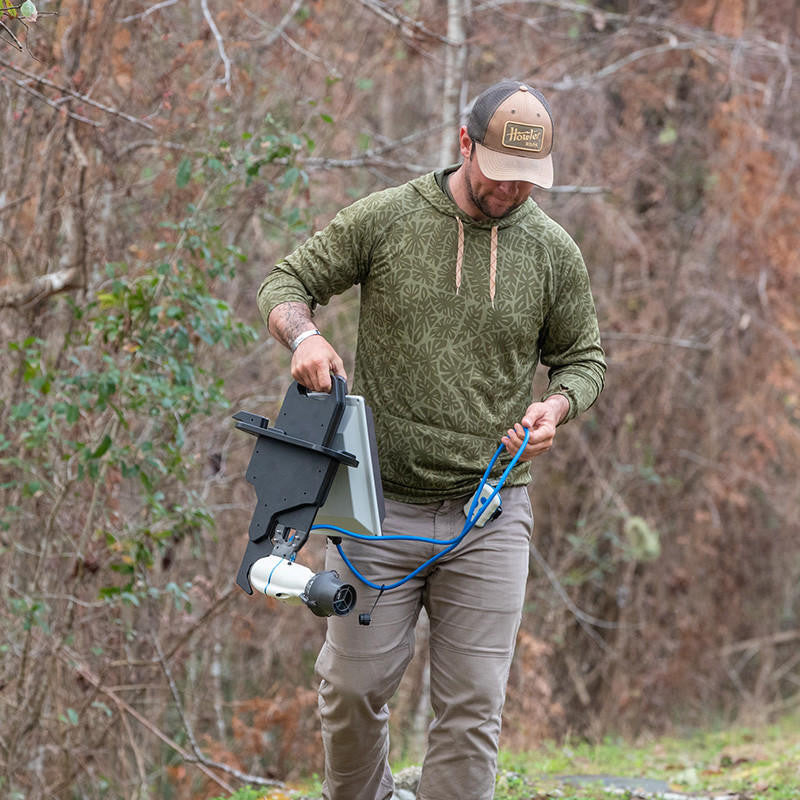 Man carrying BOTE Apex Pedal Drive Adapter with Bixpy J-2 Motor and blue power cable through wooded area.