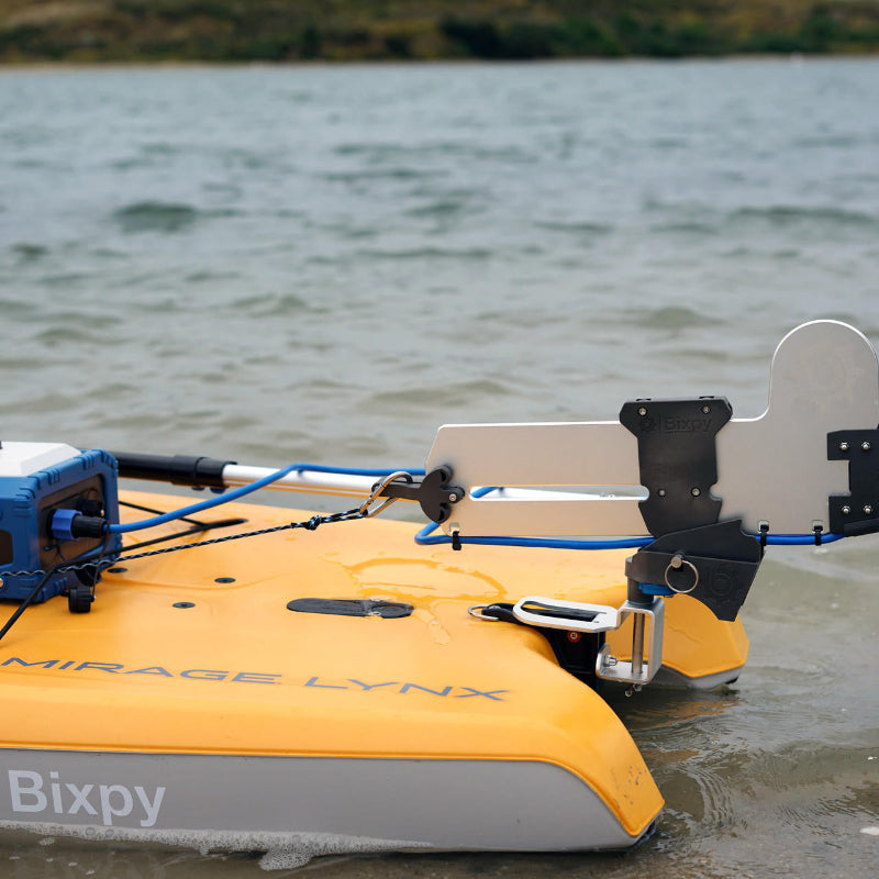 Close-up of a Bixpy Jet electric motor and battery system installed on an orange Mirage Lynx kayak, partially in shallow rippled water.