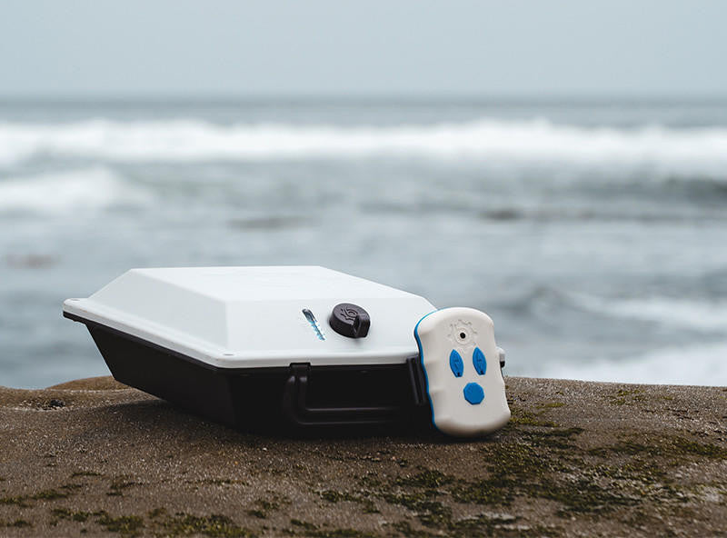 Bixpy Battery Pack and Wireless Remote on the shore, with the ocean in the background.