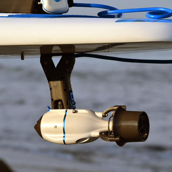 Bixpy motor mounted under a stand-up paddleboard using the SUP – Paddleboard Adapter for US Fin Box (J-1 Motors), with a blue power cable running along the deck.