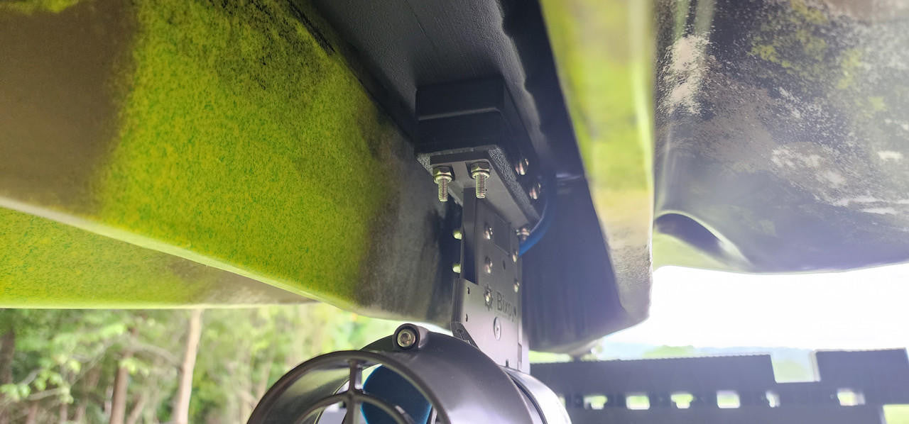 Very close-up, bottom view of a Bixpy Jet electric motor mounted to the underside of a kayak, showing the black adapter and bolts.