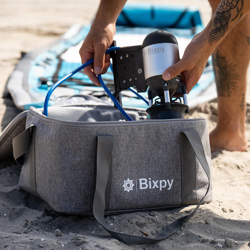Bixpy Travel Bag placed near a kayak with gear partially inside, ready for outdoor use.