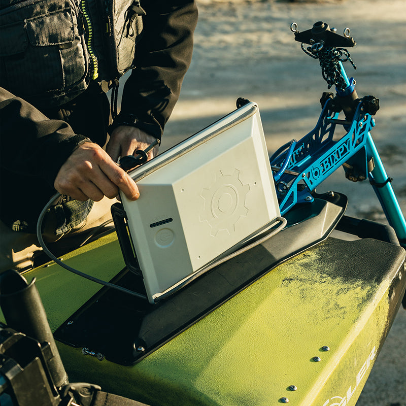 A person installing a Bixpy motor onto a watercraft using a blue mounting bracket.
