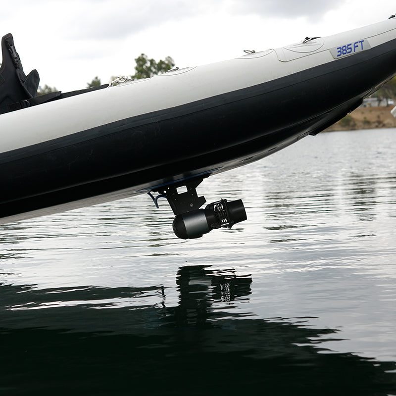 Bixpy Jet electric motor mounted beneath a black and white 385 FT inflatable boat, hovering just above the water with its reflection visible.