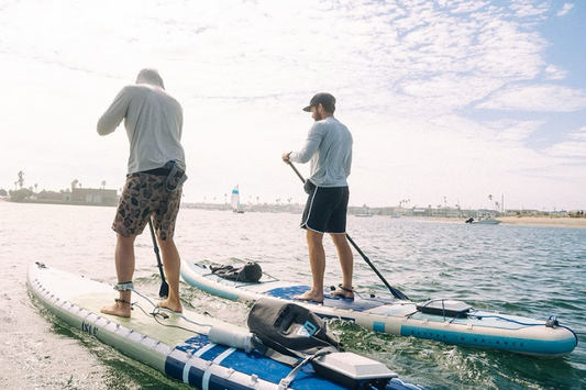 Two guys on SUPs featuring the Bixpy K-1 out on the water, bonding