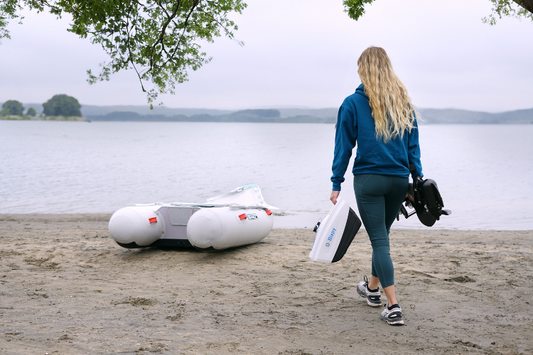 Woman holding Bixpy N3 as she walks towards her dinghy