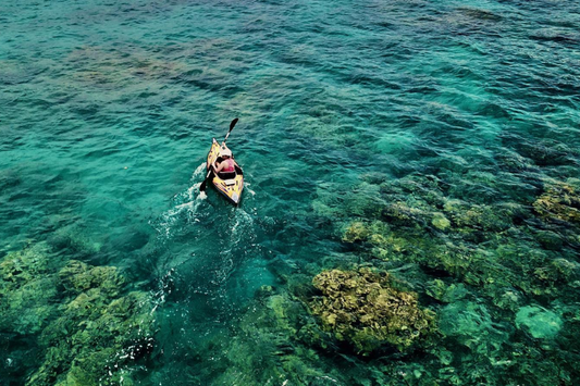 Person paddling through a reef in a kayak with a Bixpy motor