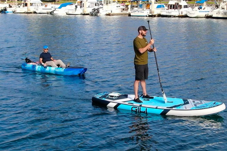 Two men on the water, one is using the Bixpy K-1 motor on a kayak while the other uses an SUP
