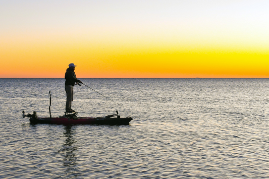 Man fishing on an SUP with a Bixpy Motor at sunset
