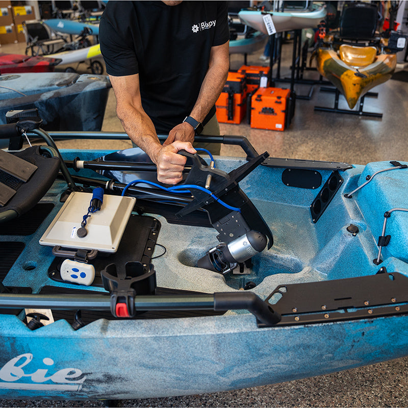 Person installing a Bixpy Jet electric motor with adapter into a blue Hobie kayak.