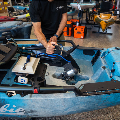 Person installing a Bixpy Jet electric motor with adapter into a blue Hobie kayak.