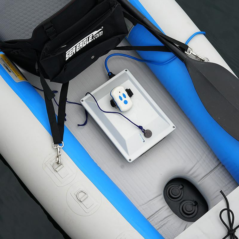 Close-up of a Bixpy battery and remote control on a grey and blue Sea Eagle inflatable kayak with a paddle.
