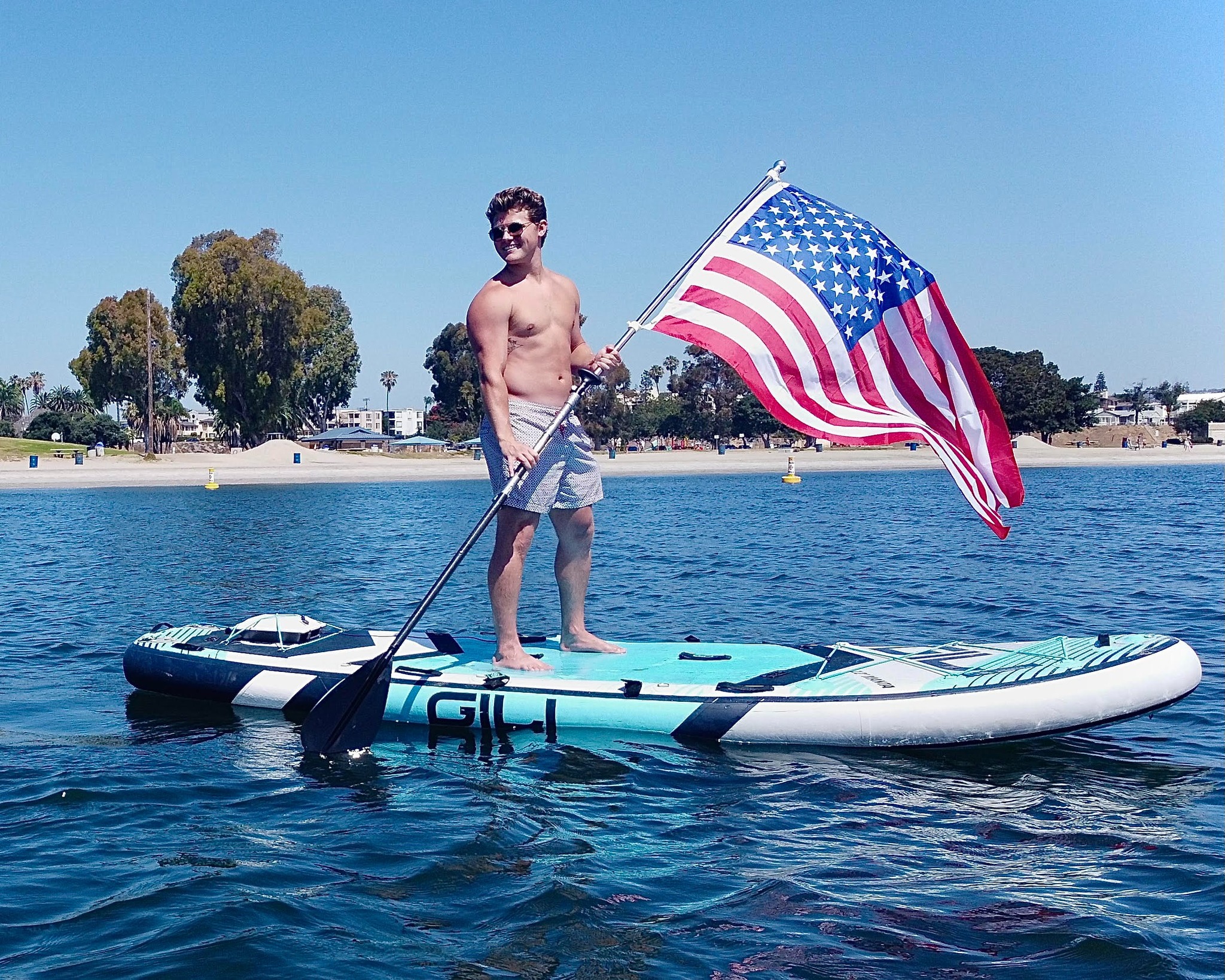 Man on standup paddleboard with American flag and Bixpy motor