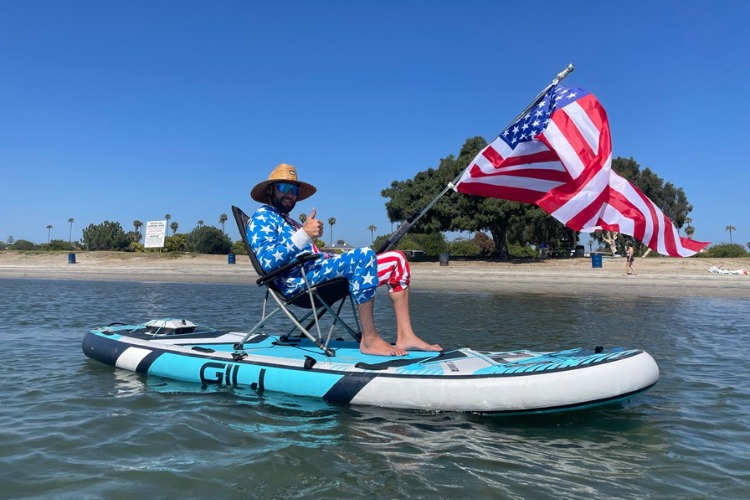 Man on paddleboard in chair with American flag and Bixpy motor