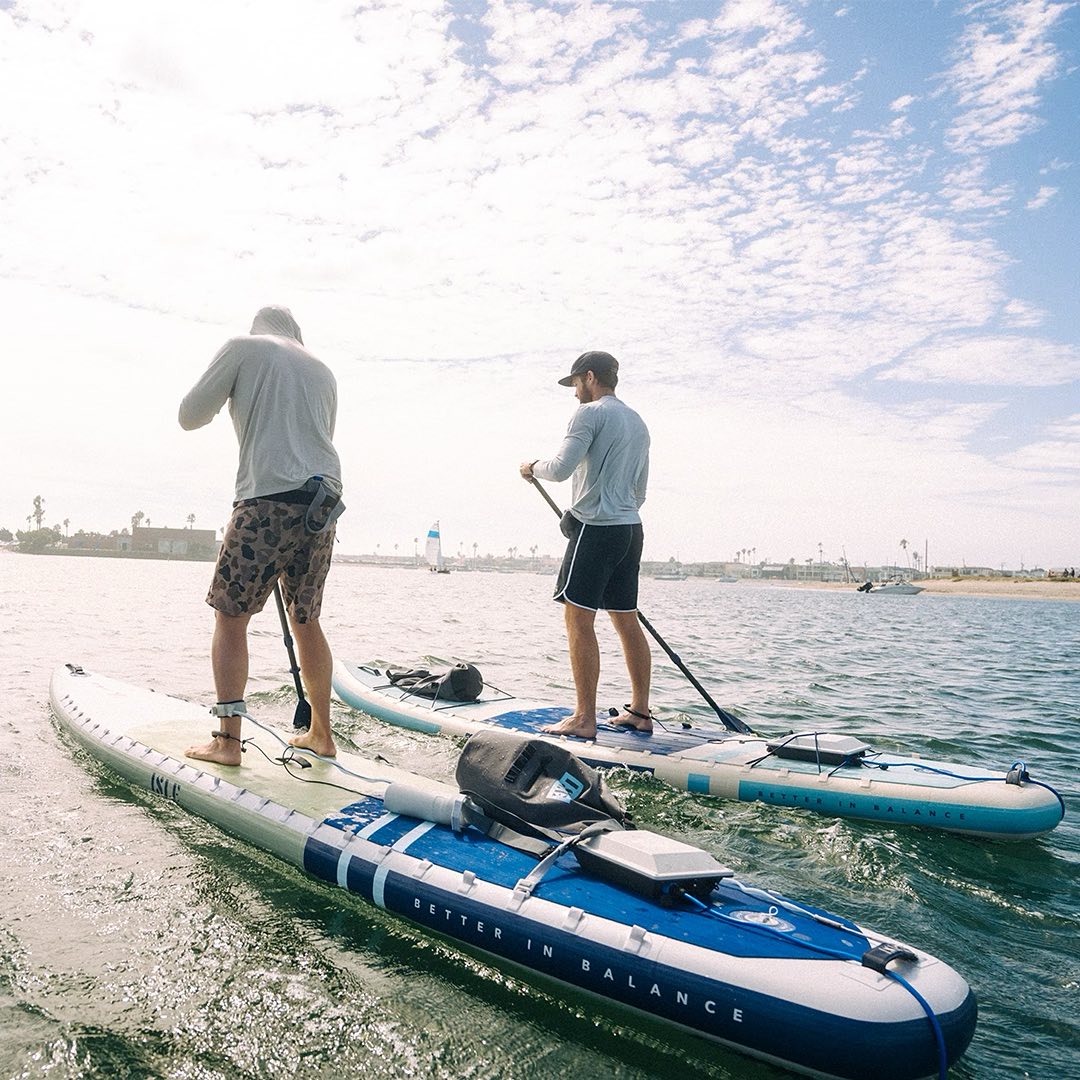 Two men on standup paddleboards using Bixpy battery and motor