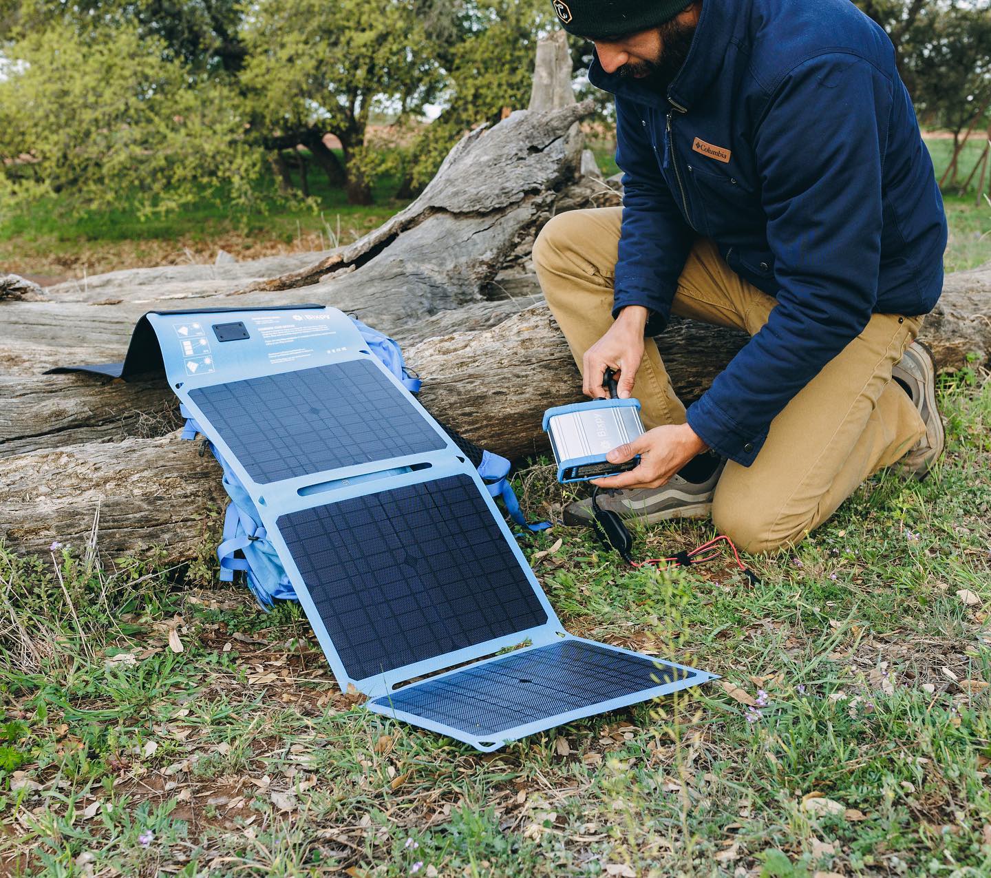 Man using solar panels to charge Bixpy Power Bank while on a camping trip